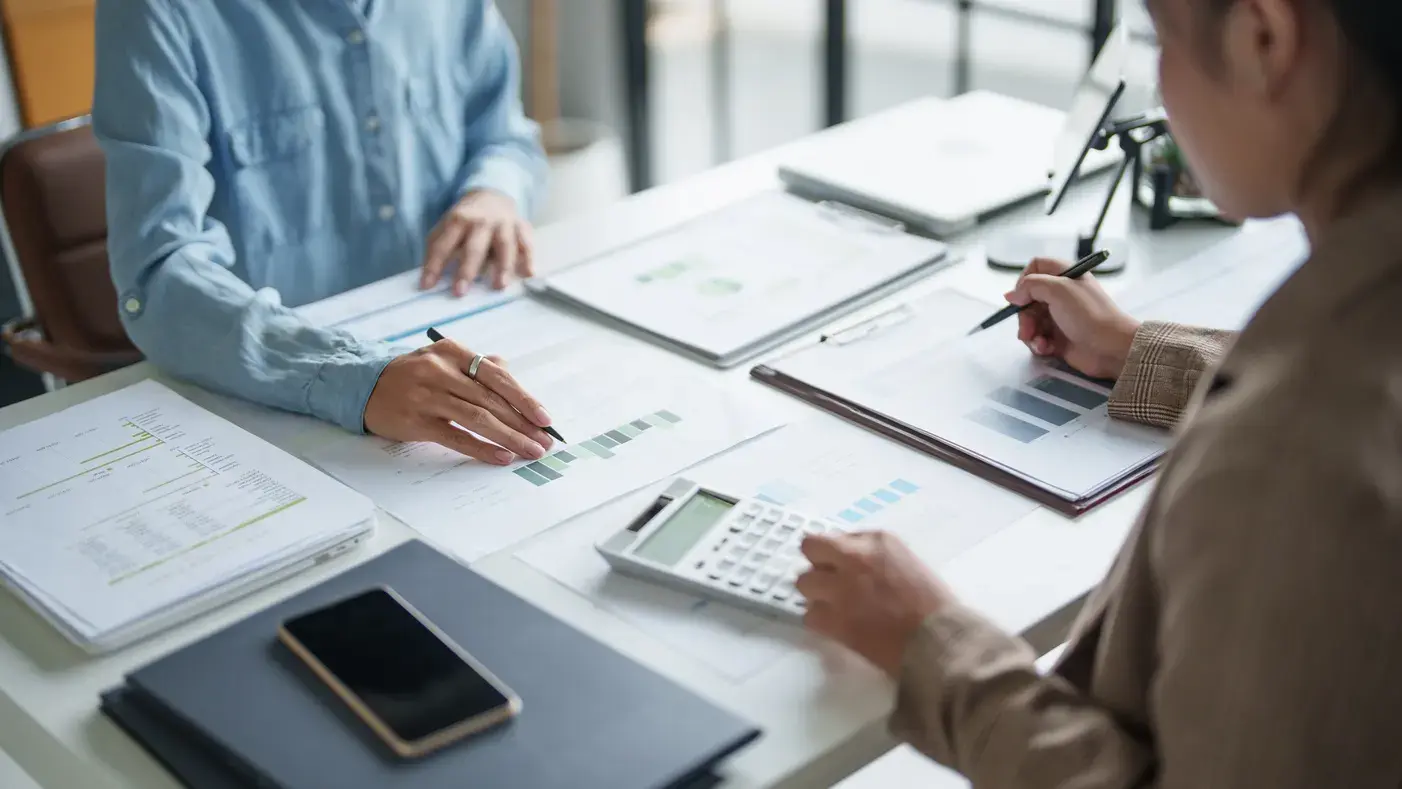 Hands working through financial documents with a calculator