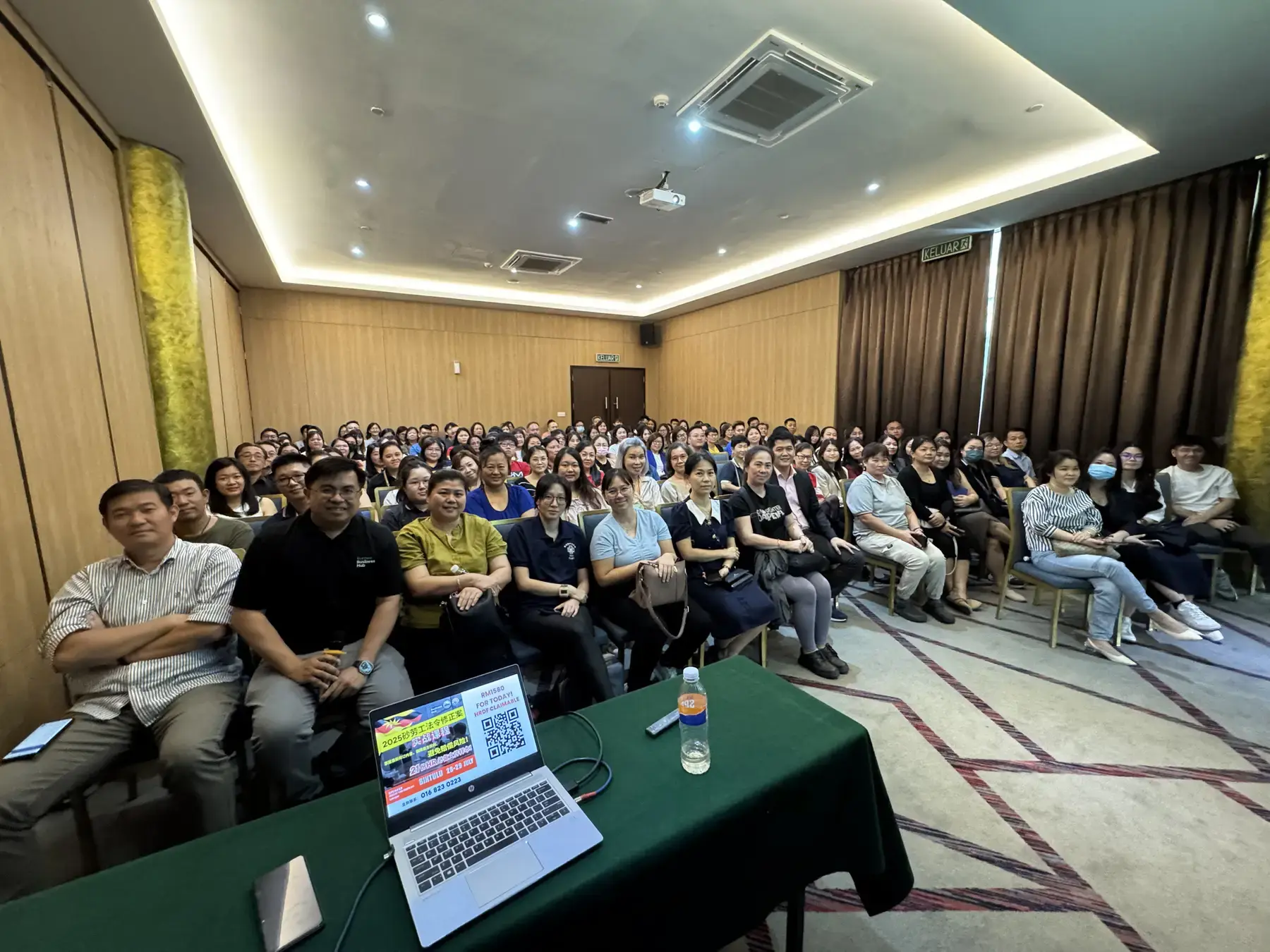 A presenter's laptop on the table in front of a seminar audience